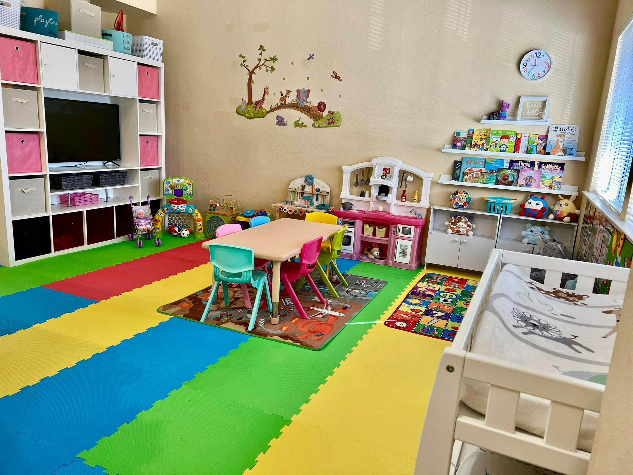 Playroom with colorful floor mats, small table and chairs, and toy shelves