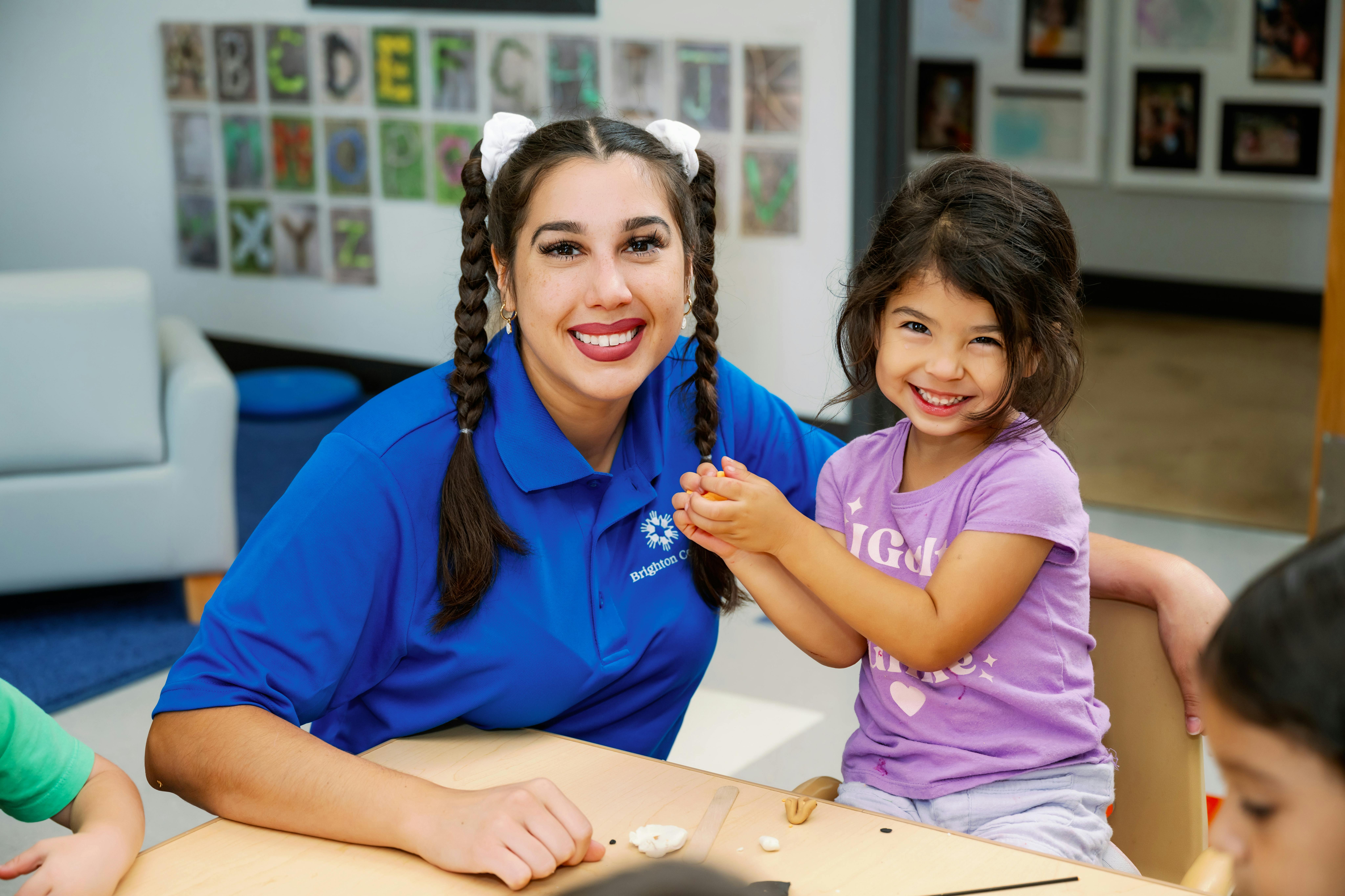 Adult and child smiling at a table in a classroom