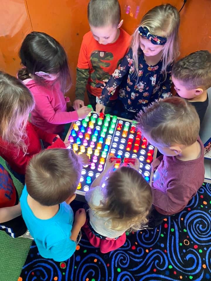 Children playing with a light-up pegboard