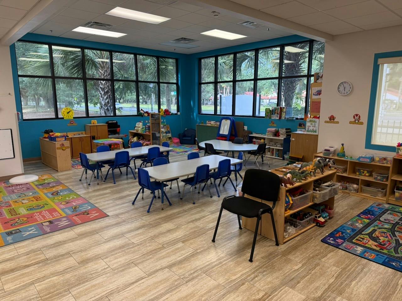 Empty preschool classroom with small tables and chairs