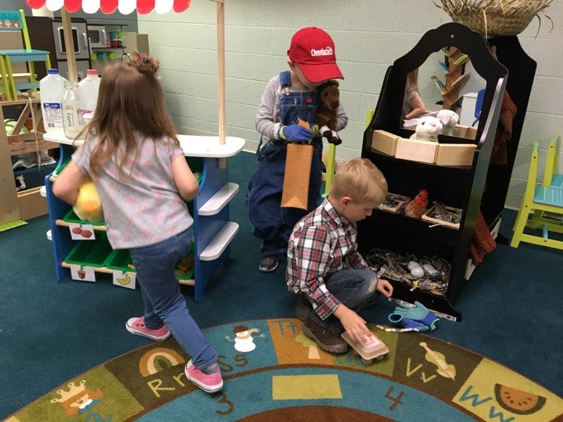 Three children playing in a classroom
