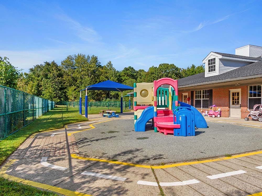 Playground with colorful play structure, fence, and building