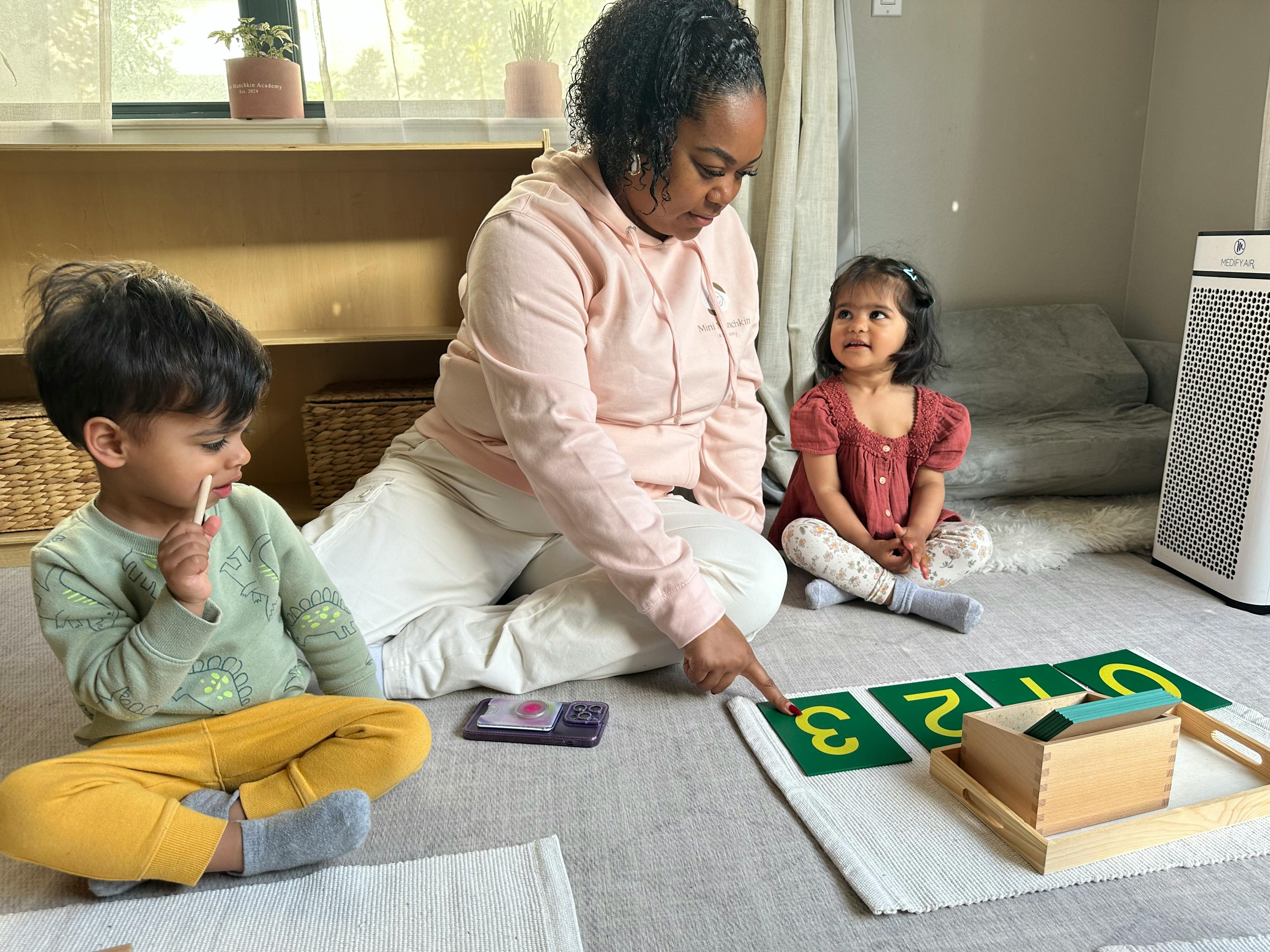 Adult and two children on floor with number cards