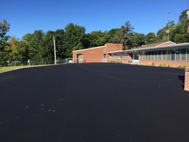 Newly paved asphalt parking lot in front of a brick building