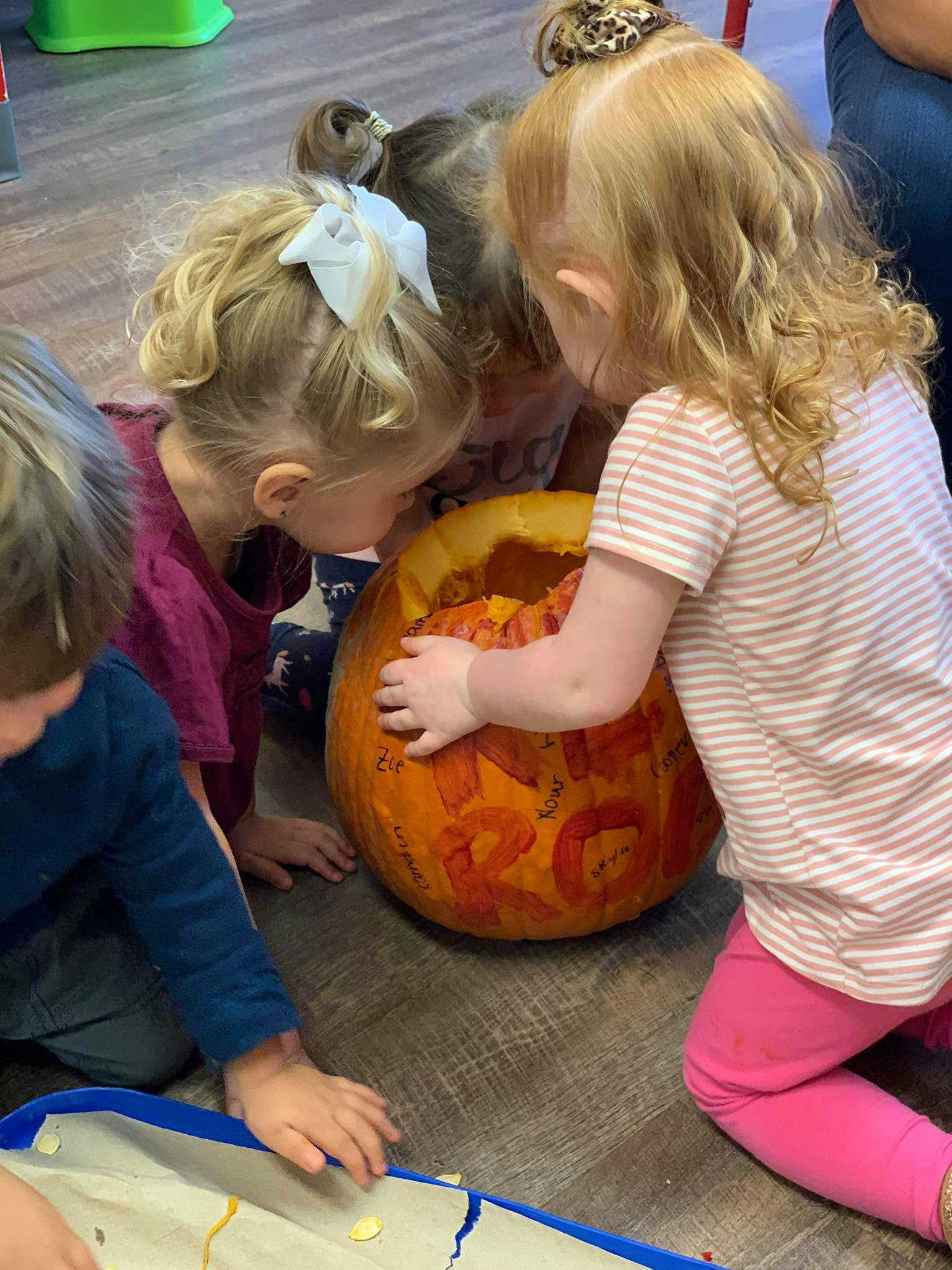 Children gathered around a pumpkin