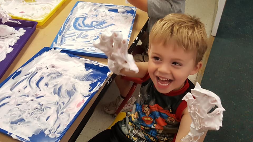 Child with shaving cream on hands and arms