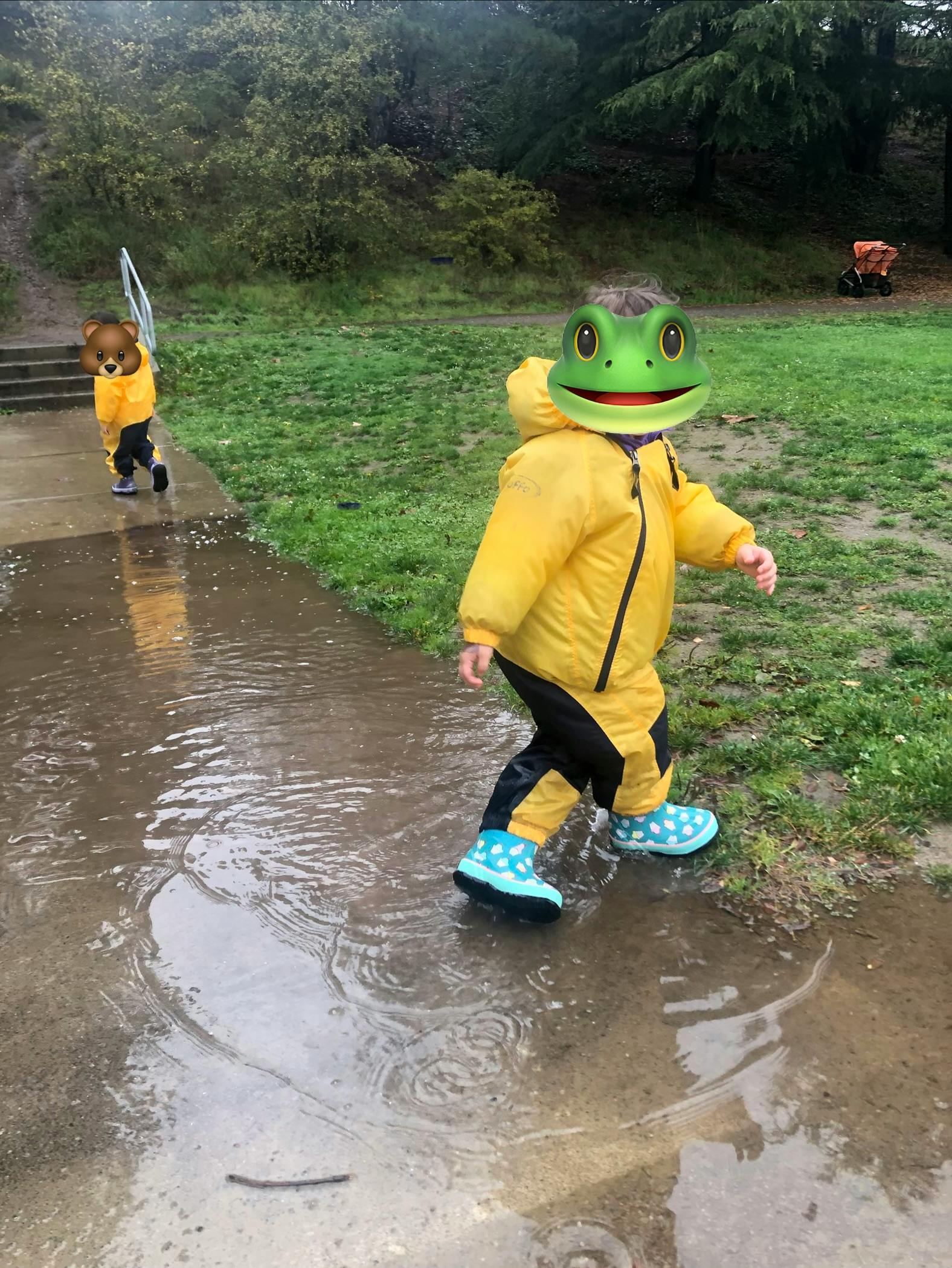 Children in yellow rain gear walking through a puddle outdoors