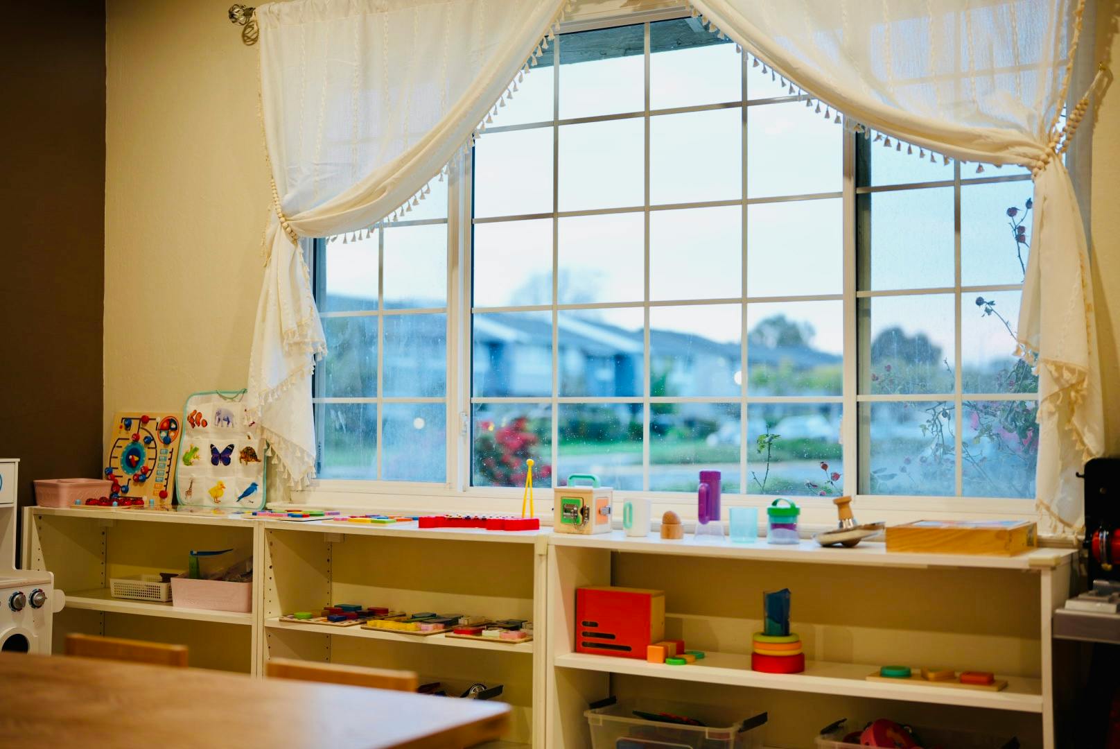 Window with white curtains and shelves with various items below