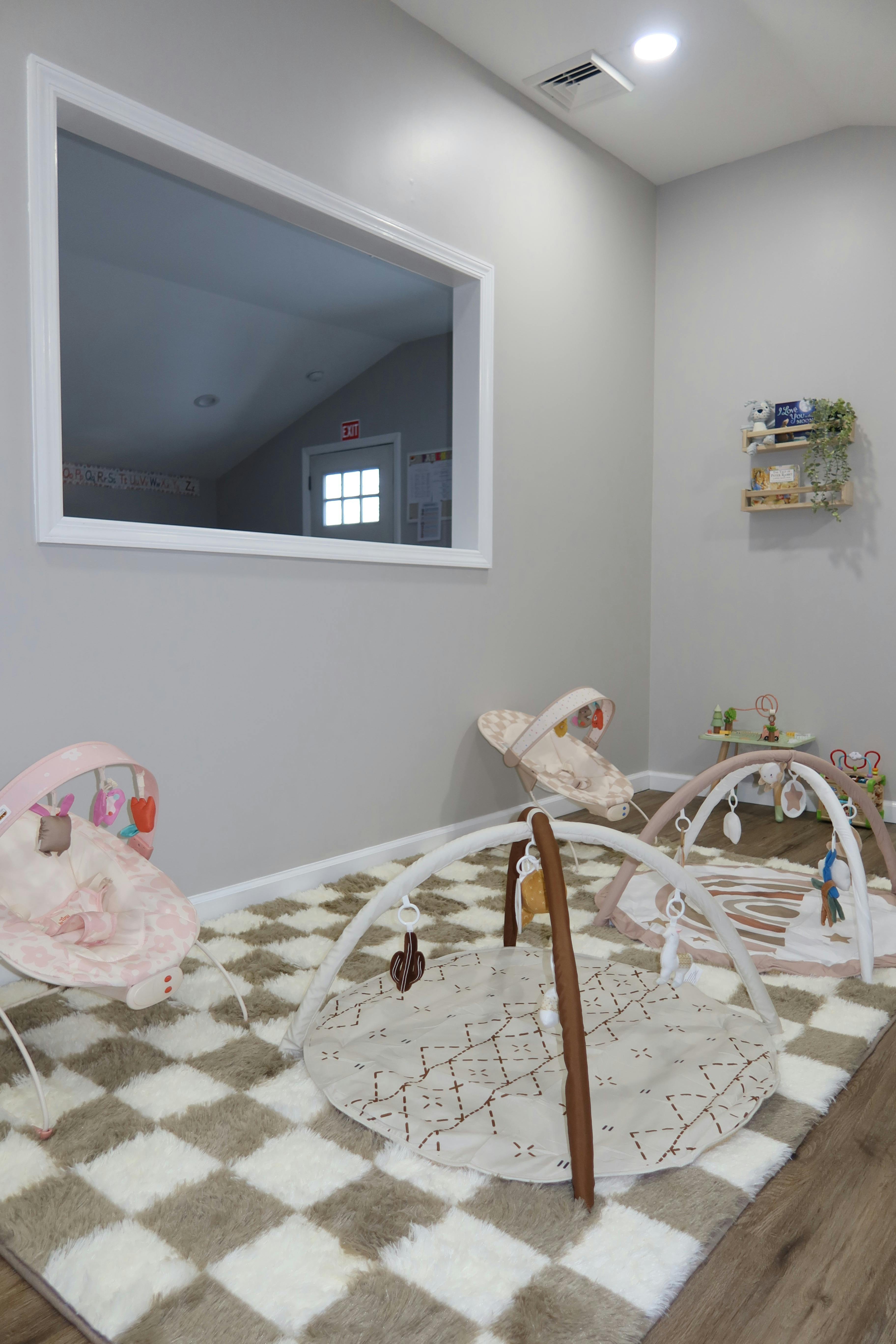 Baby play area with activity mats and bouncers on a checkered rug