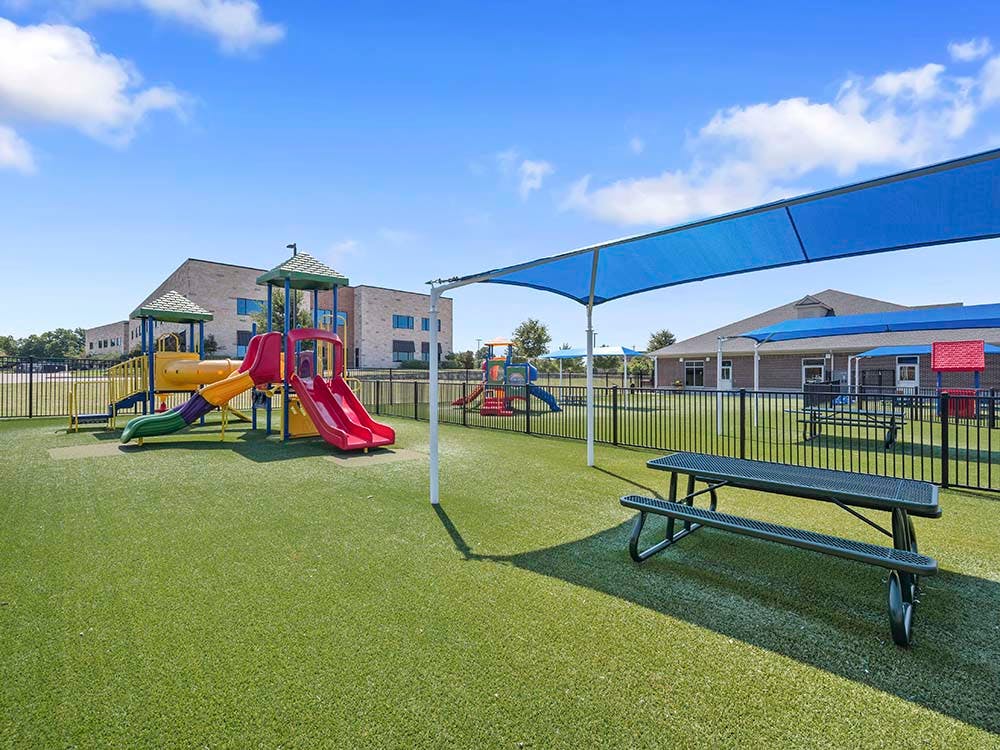 Outdoor playground with colorful slides, climbing structures, and picnic tables