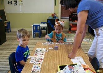 Adult and two children playing a card game at a table
