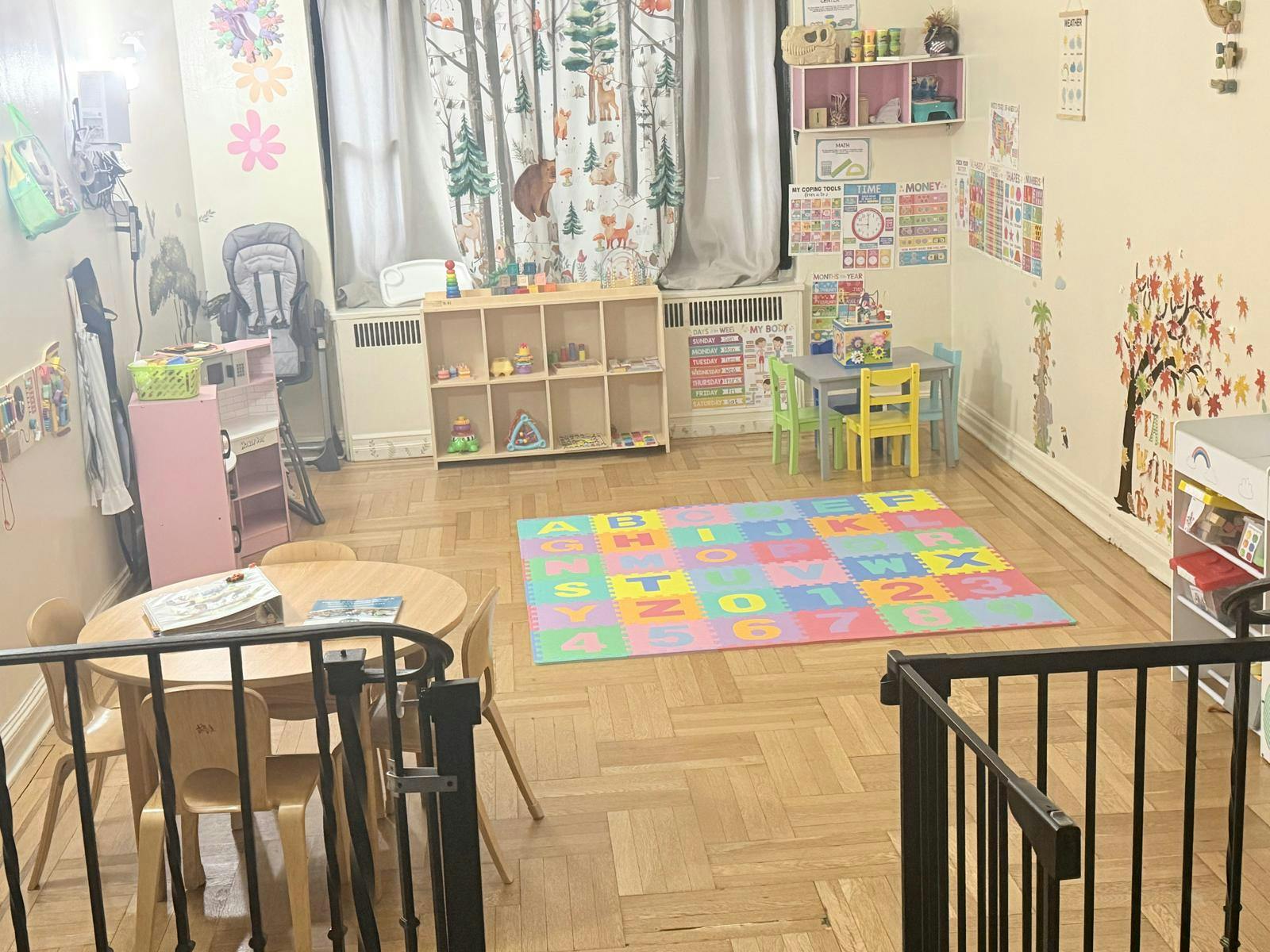 A playroom with small tables, chairs, and an alphabet playmat on a wooden floor