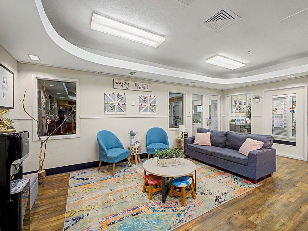 Lobby area with a blue couch, two blue chairs, and a colorful rug