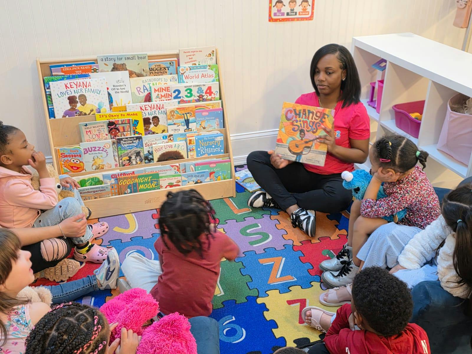 Adult person reading to a group of children in a classroom