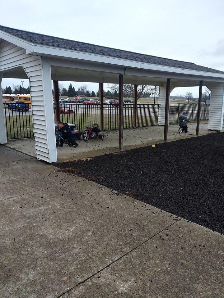 Children on tricycles under a covered walkway
