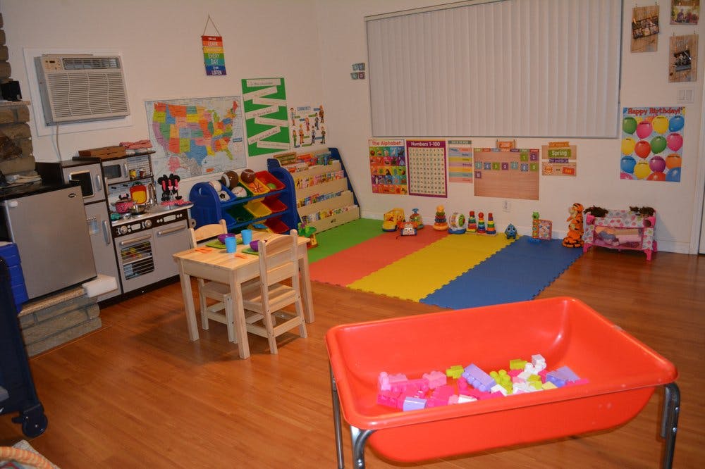 Playroom with a small table and chairs, play kitchen, and colorful floor mats