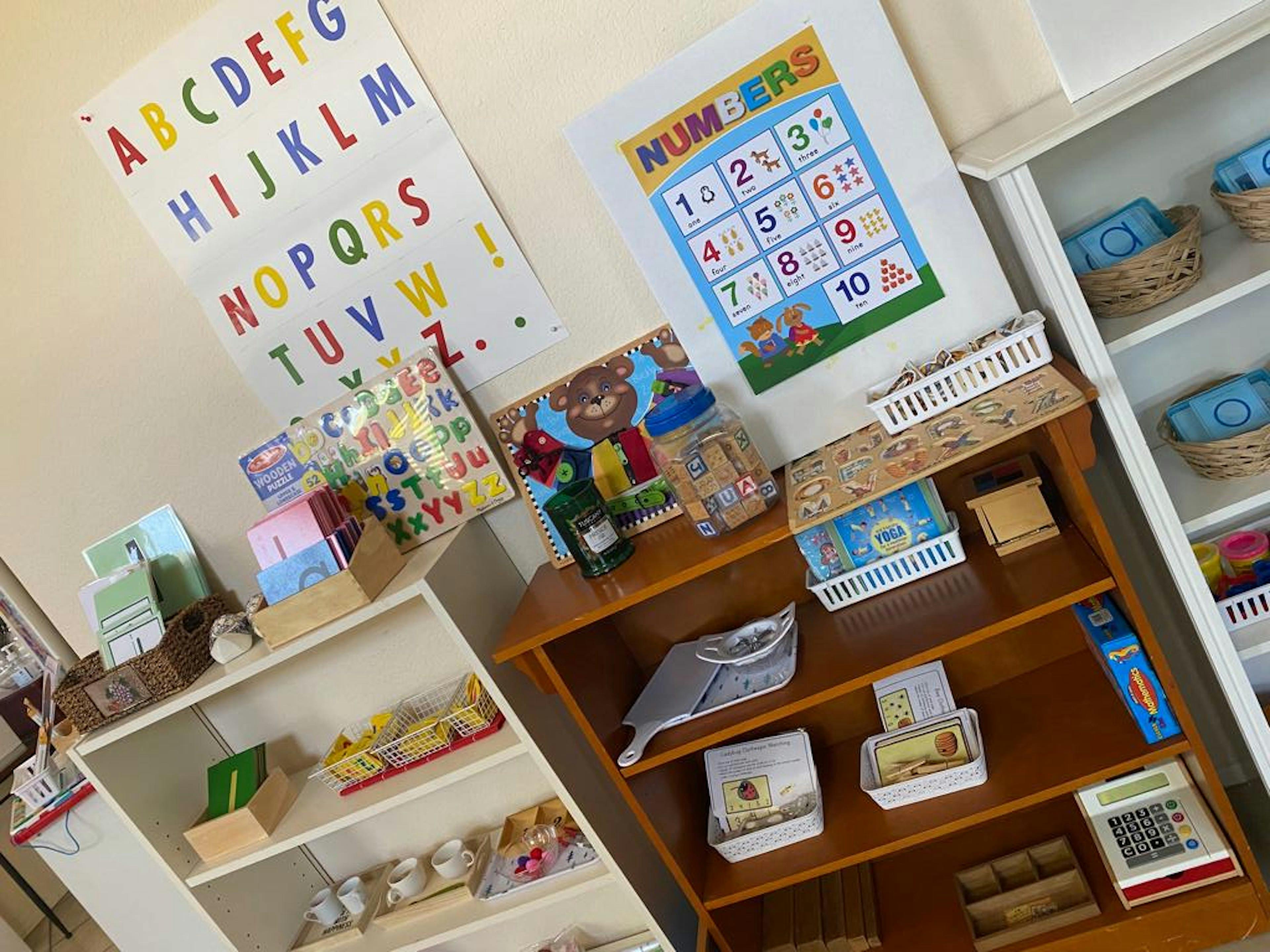 Classroom with alphabet and numbers charts on the wall, shelves with learning materials