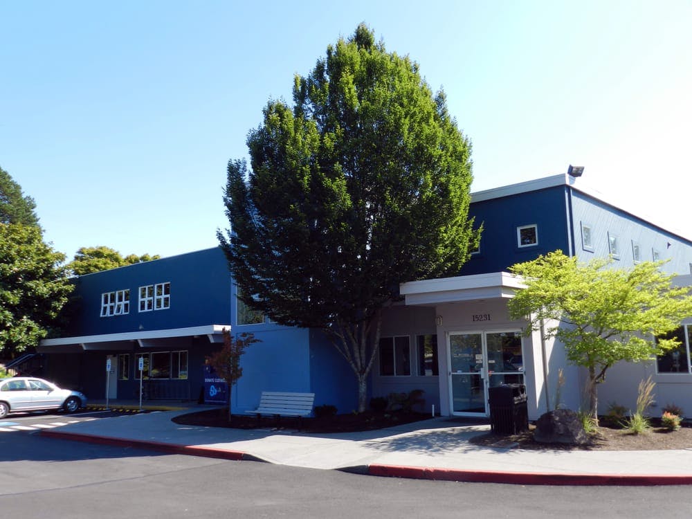 Exterior of a blue building with a large tree in front