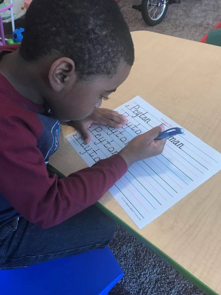 Child writing on a worksheet at a table