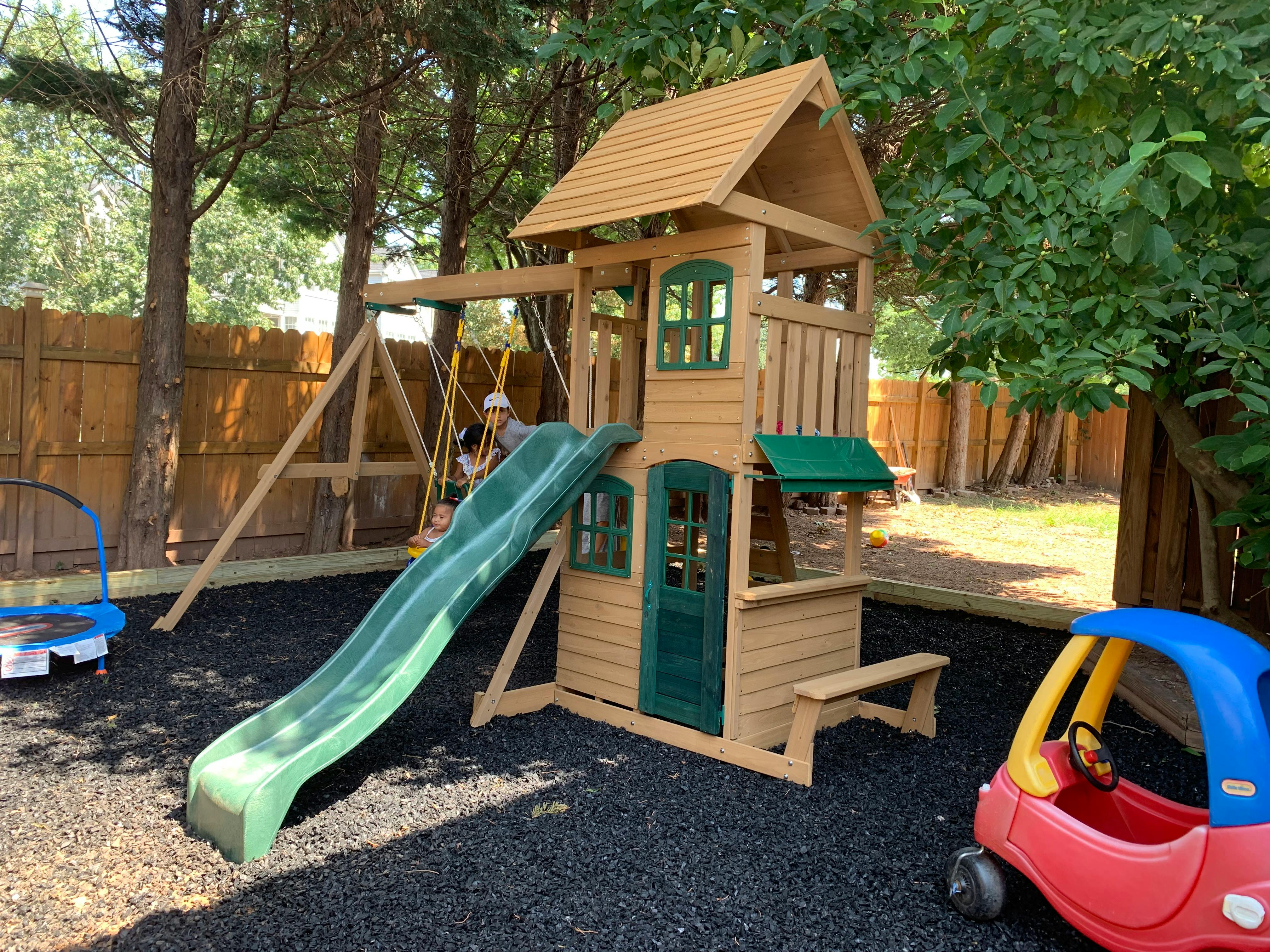 Playground with three children on swings and a slide