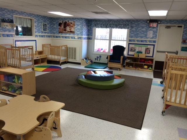 Cribs, small tables, and chairs in a childcare room
