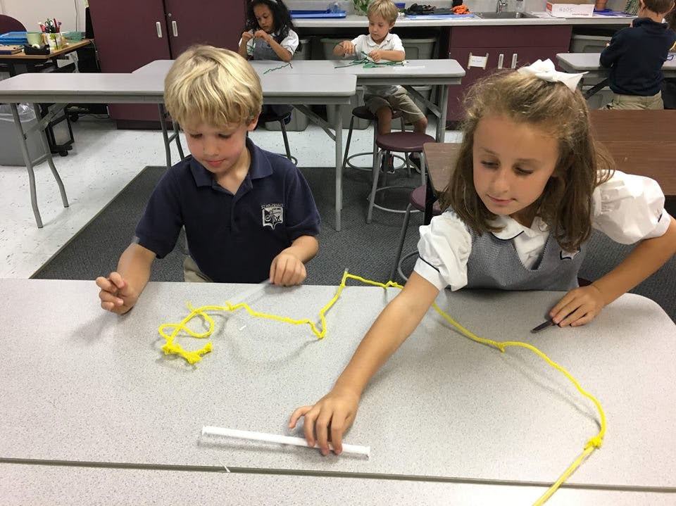 Two children at a desk with yellow string