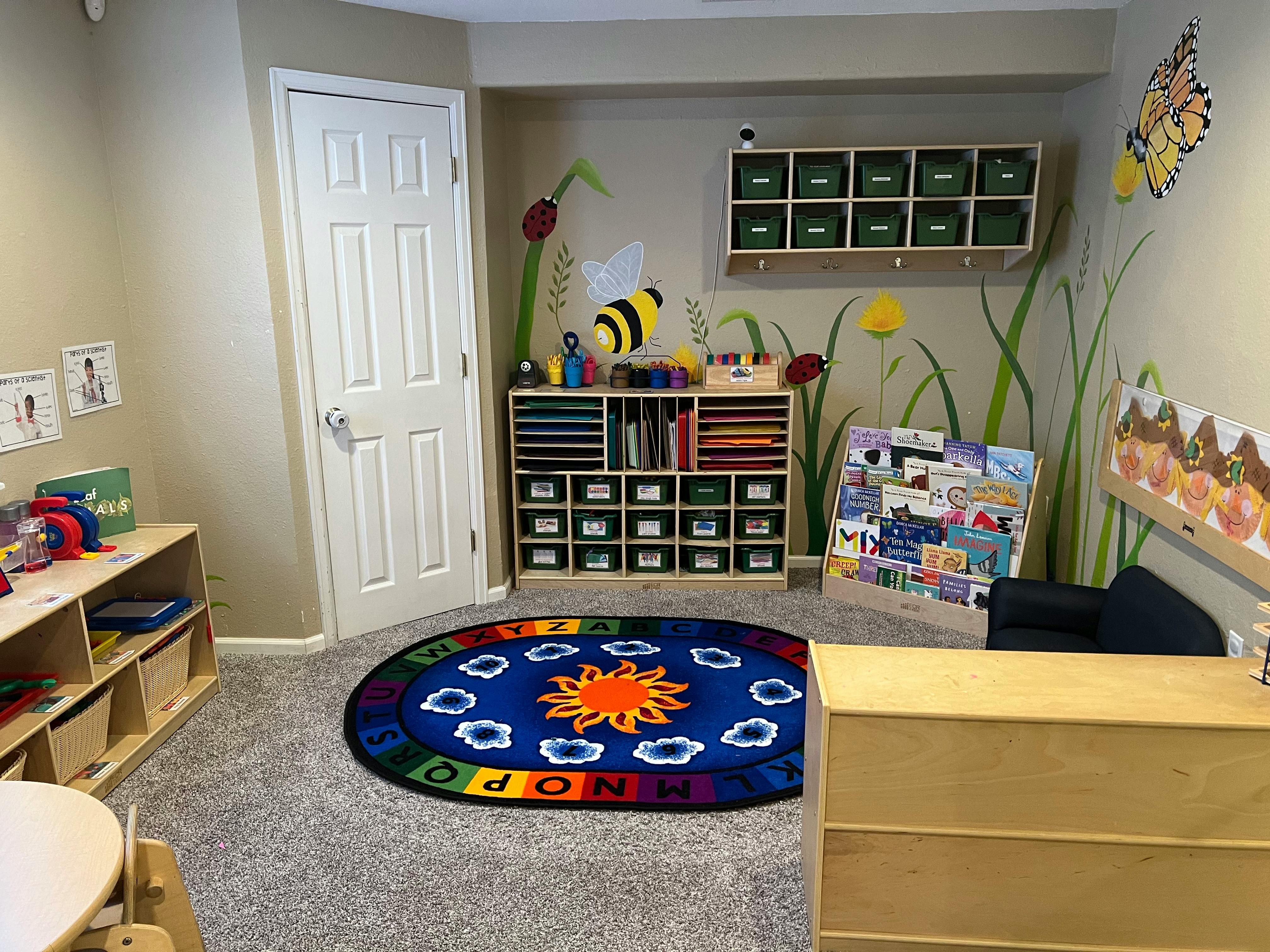 Playroom with a sun and alphabet rug, storage shelves, and wall decorations