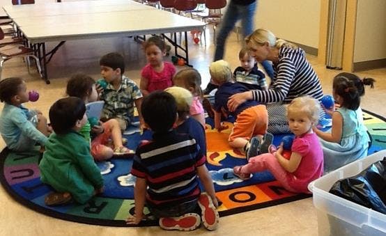 Adult and children sitting on a rug in a classroom