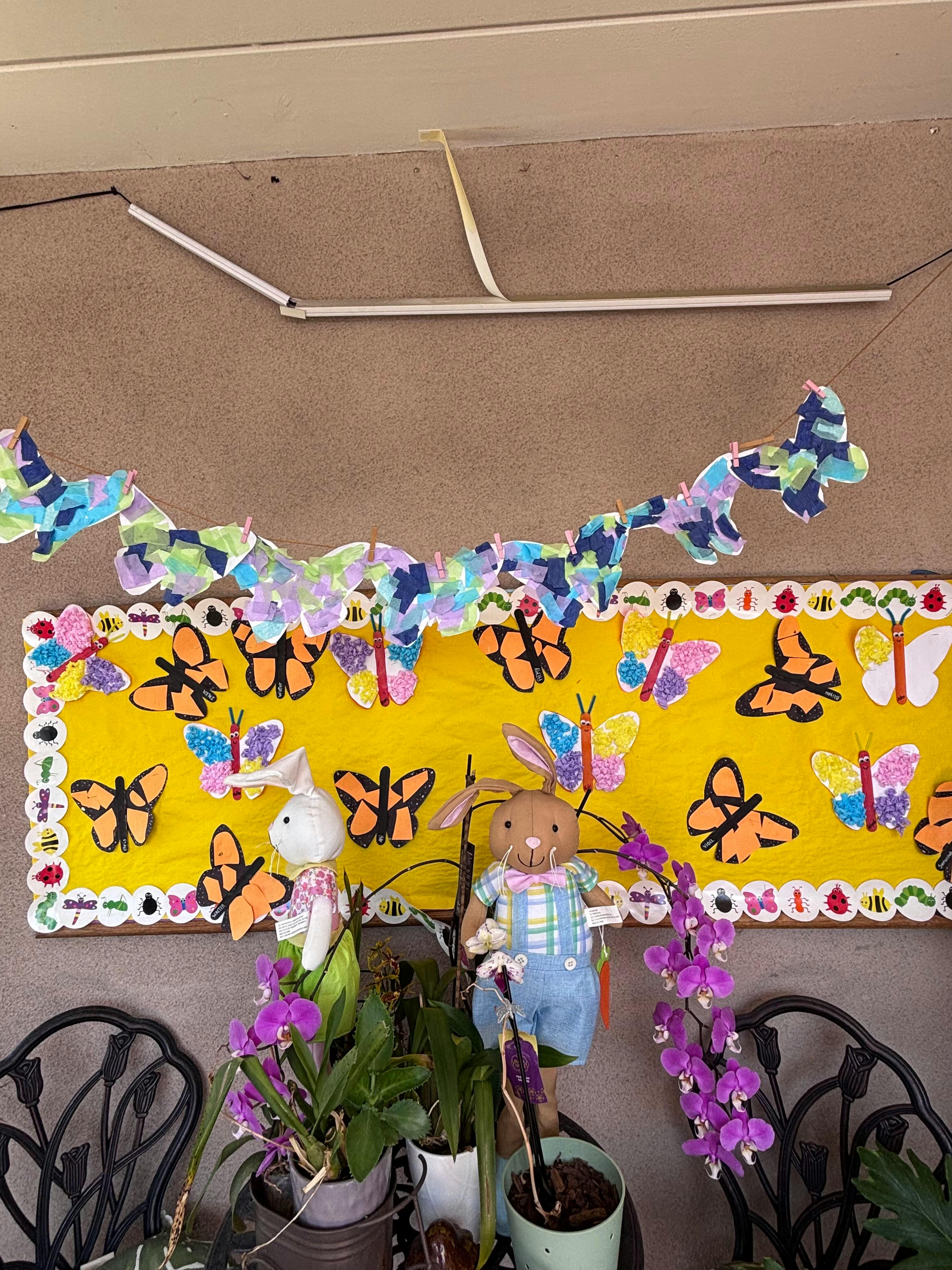 Decorative wall display with paper butterflies and two plush rabbits