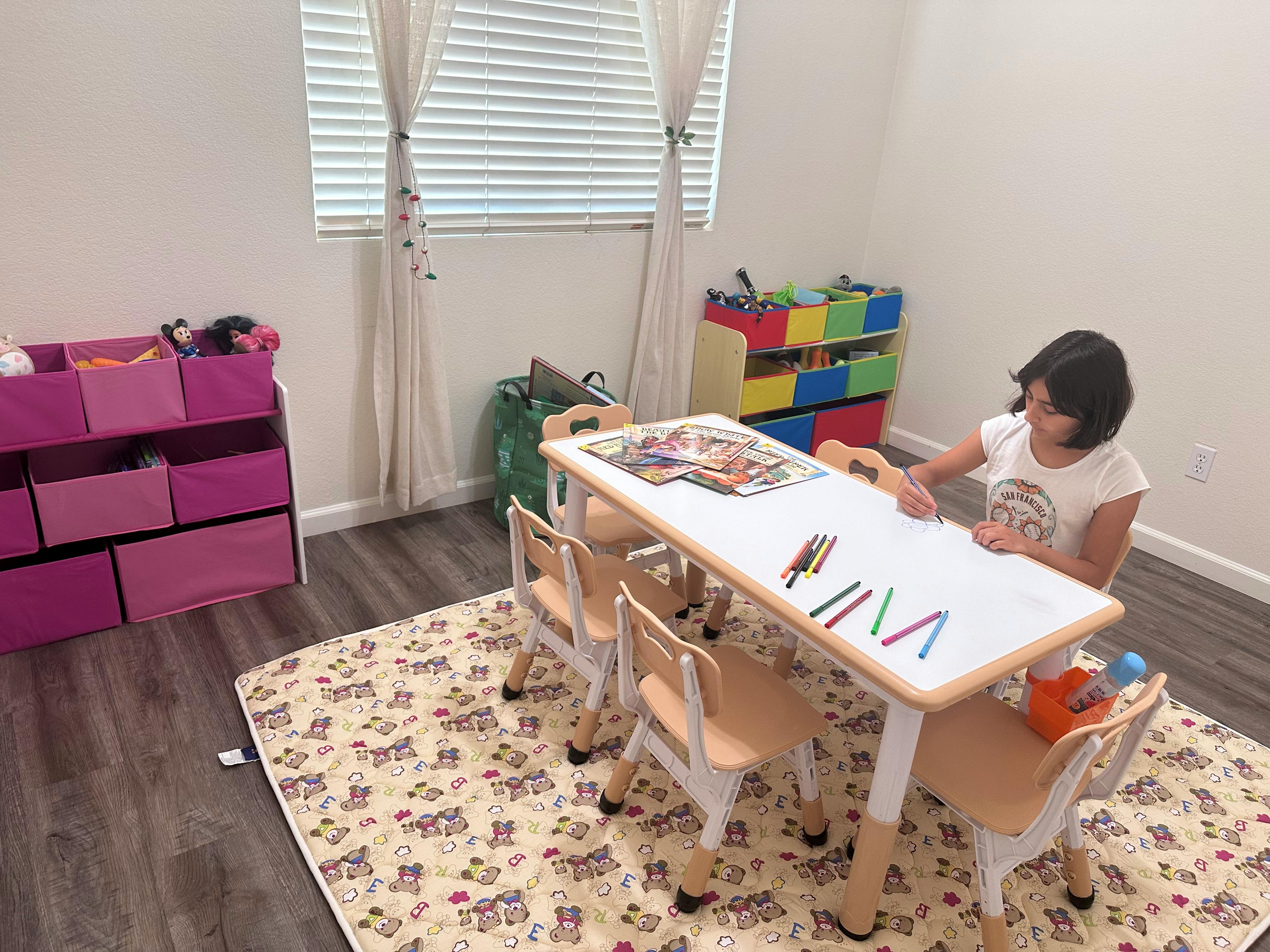 Child sitting at a small table with crayons
