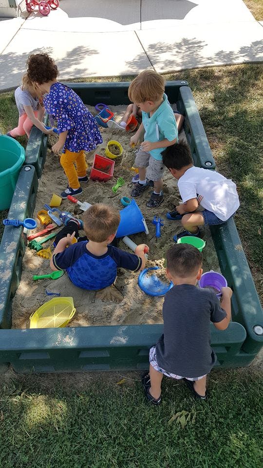 Children playing in a sandbox with toys