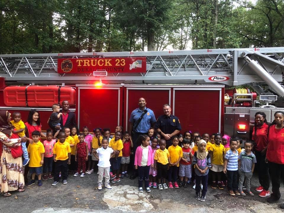 Group of adults and children posing in front of a fire truck with "TRUCK 23" on it