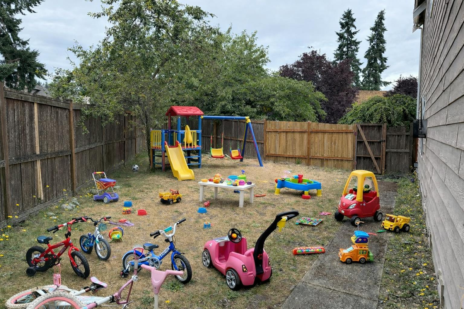 backyard full of various children's toys including bikes, cars, and playsets