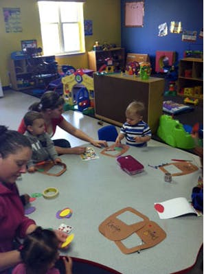 People and children sitting at a table doing crafts