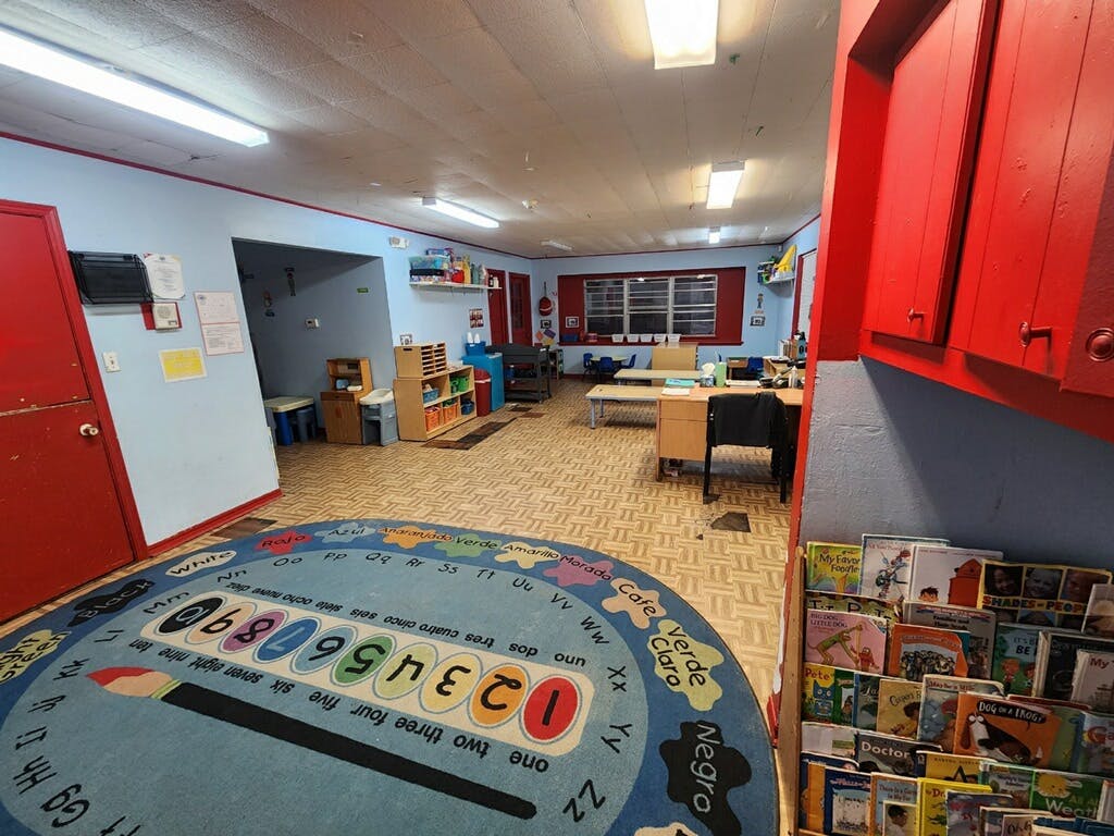 Classroom with a colorful rug, tables, chairs, and shelves