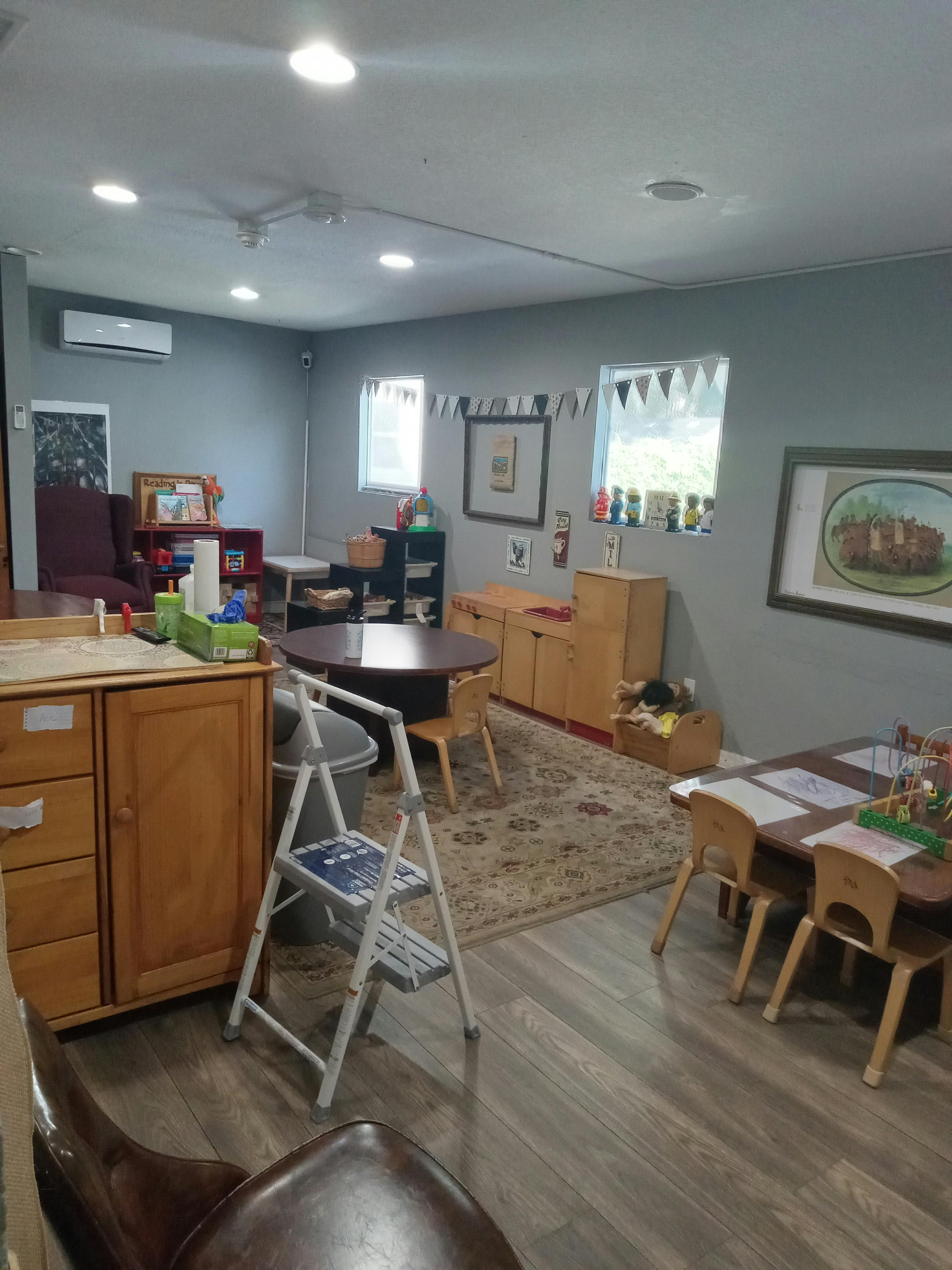 A room with small tables and chairs, a rug, and cabinets