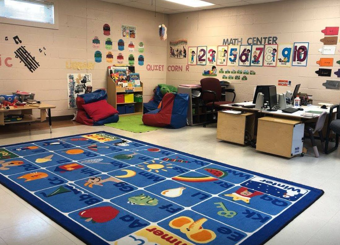 Classroom with a blue alphabet rug, beanbag chairs, and a math center