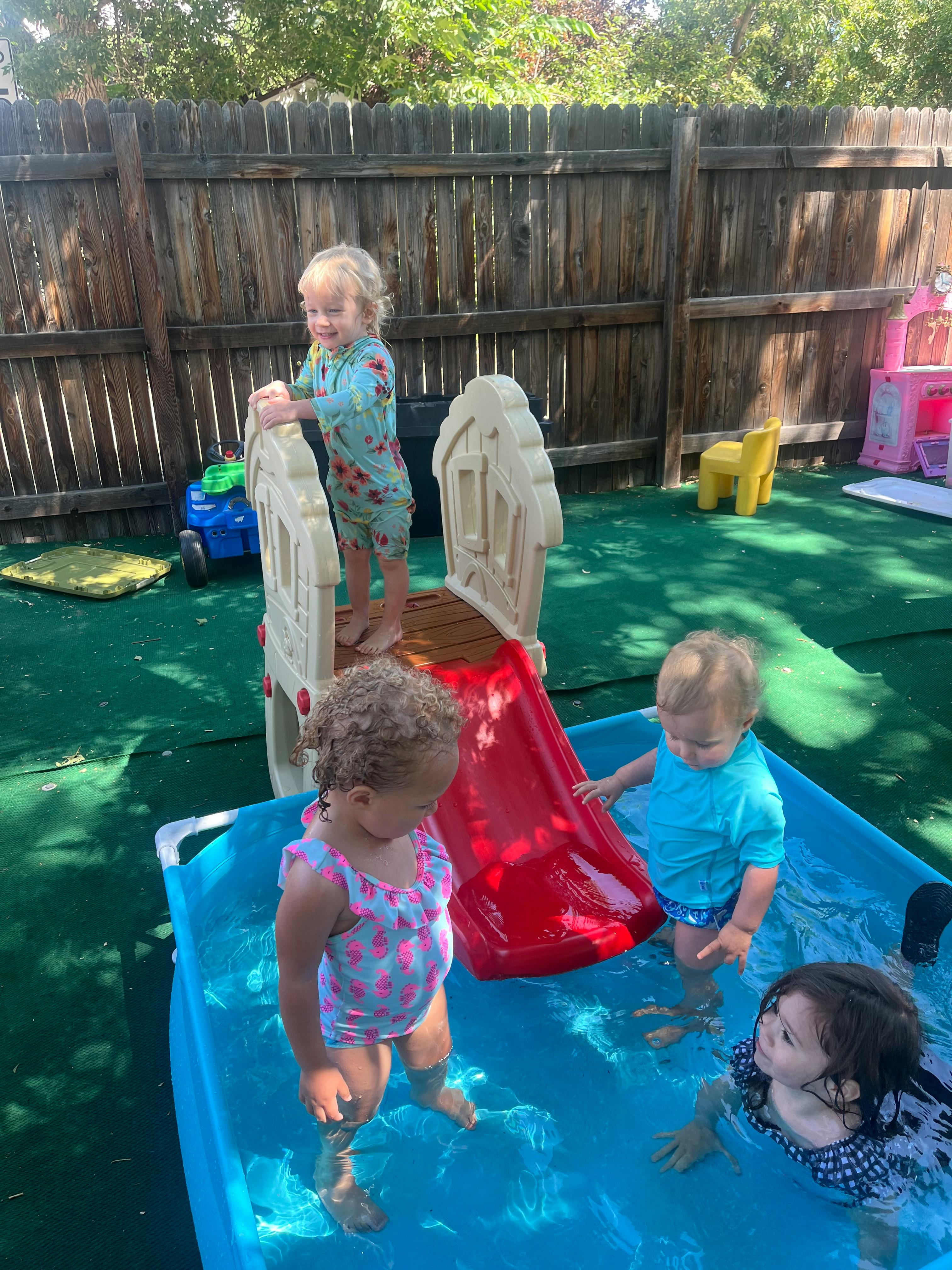 Children playing in a small pool with a slide