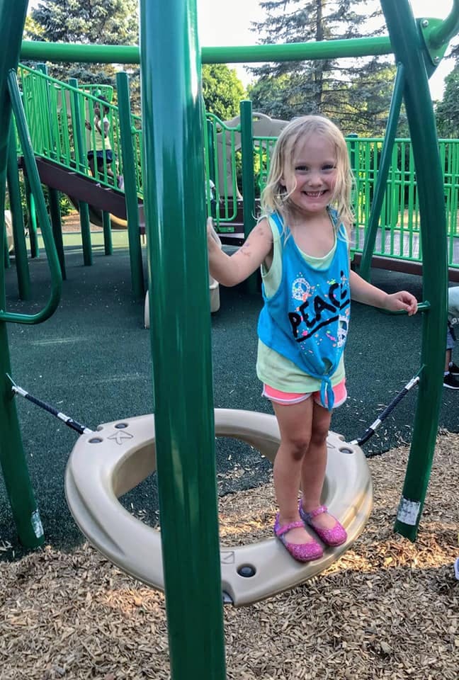 Child standing on a playground spinner
