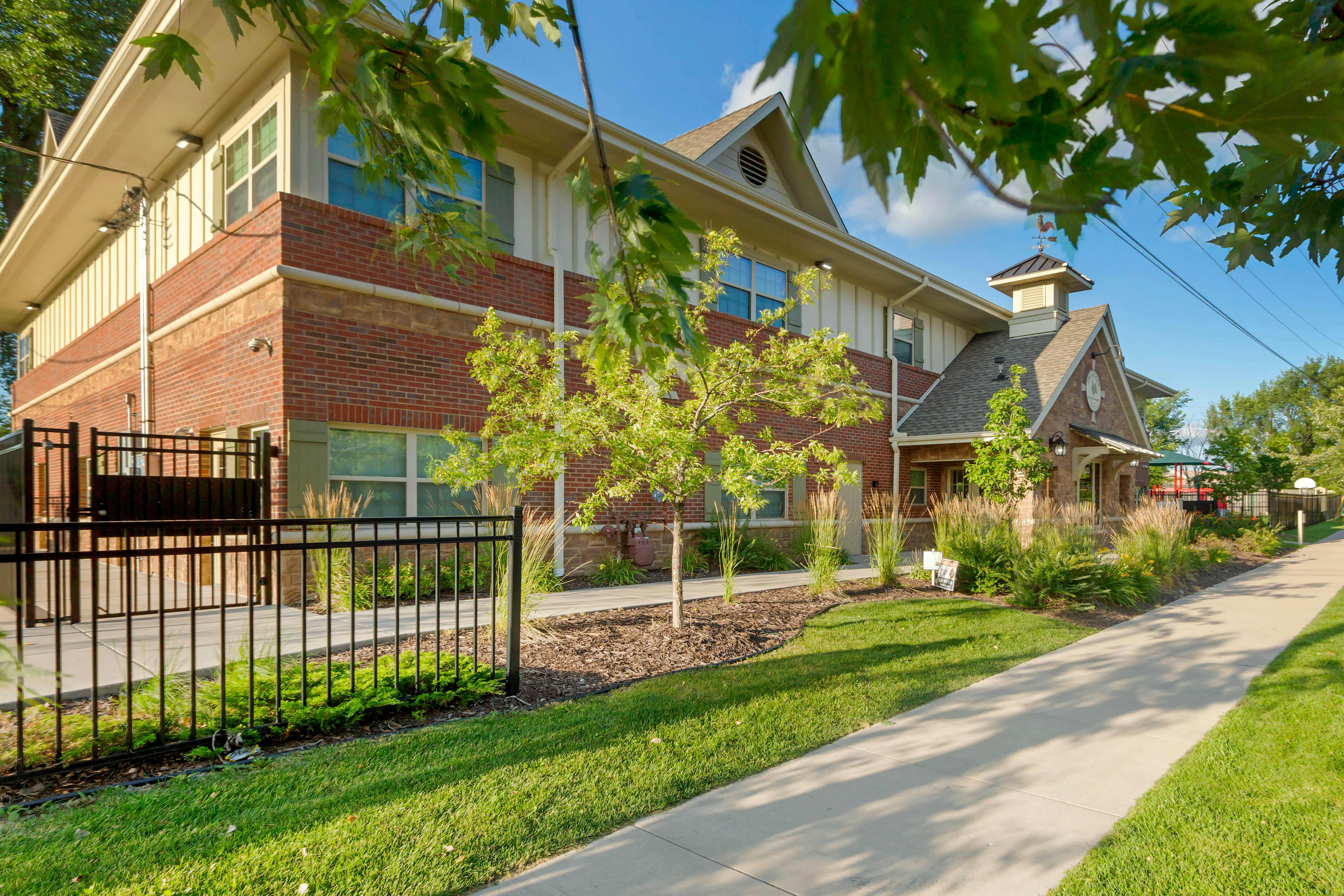 Building exterior with brick and siding, sidewalk, and green grass