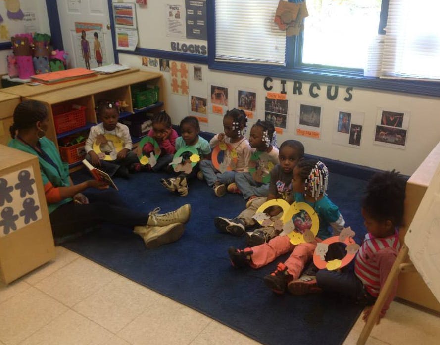 Person reading to a group of children in a classroom