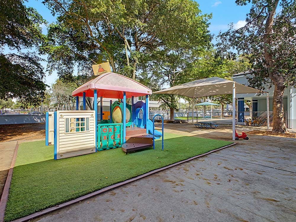 A colorful playground set with a red roof on artificial grass