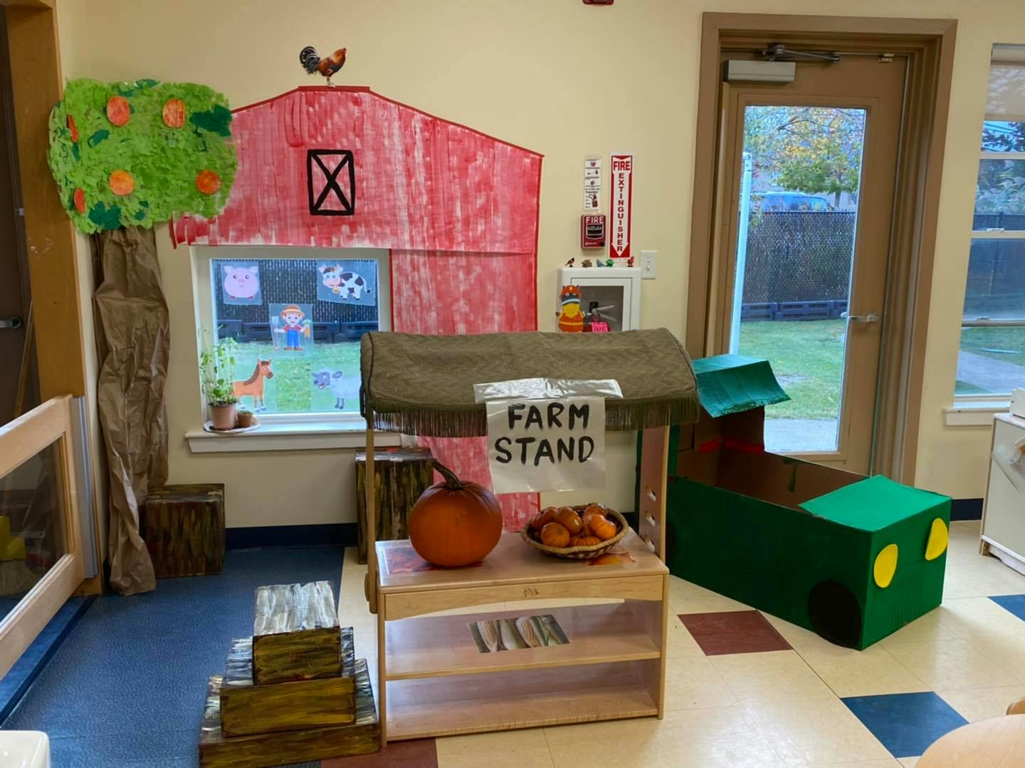 Playroom with a farm stand, a red barn cutout, and a green train toy