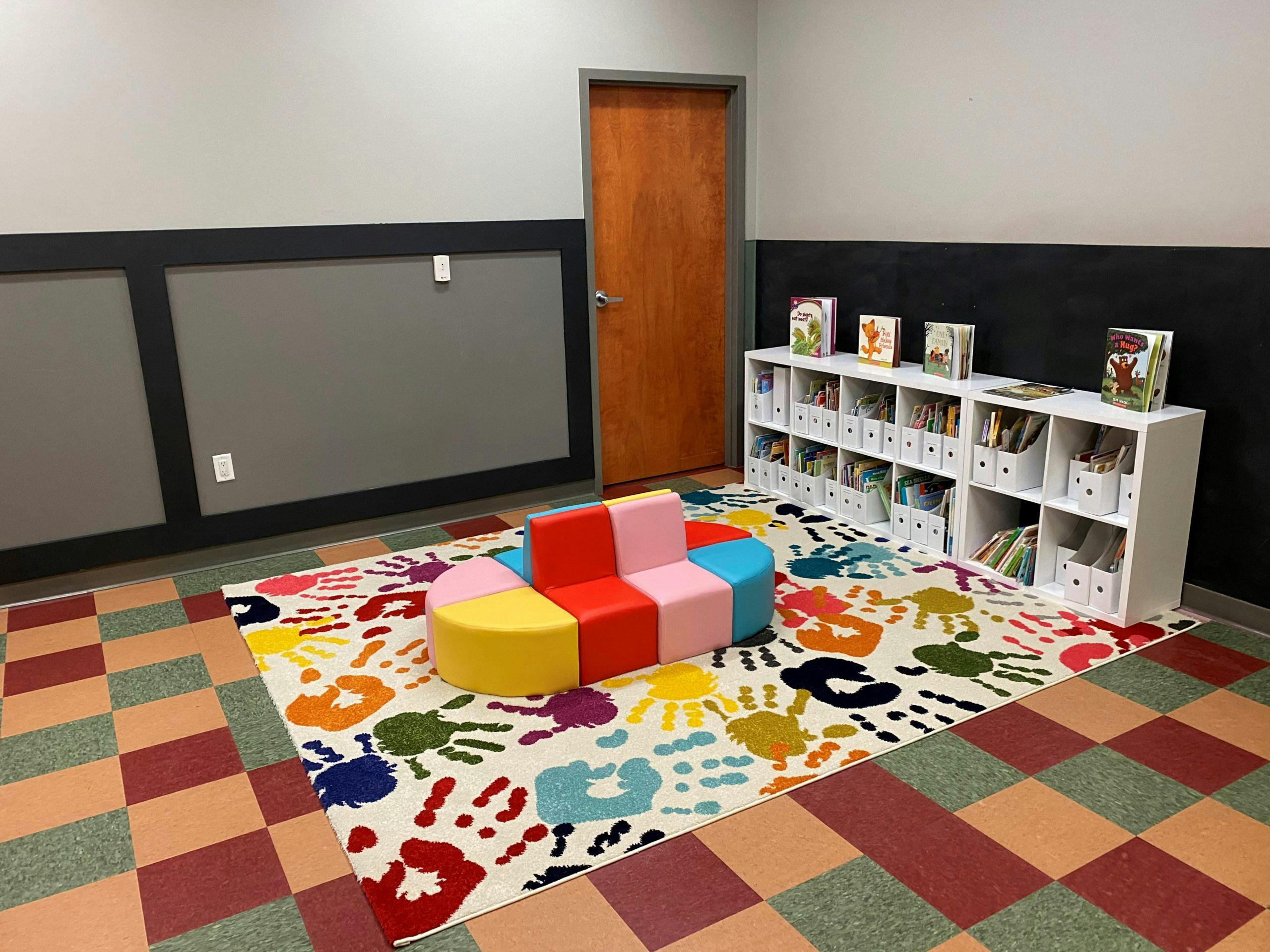 Children's play area with colorful rug, modular seating, and bookshelves