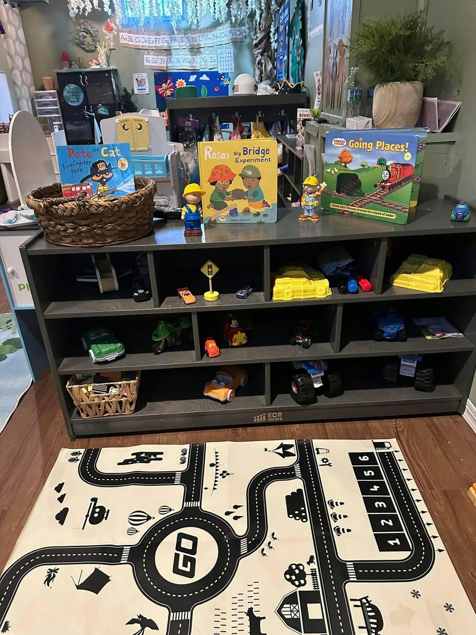 Books and toys on a shelf with a road map rug on the floor
