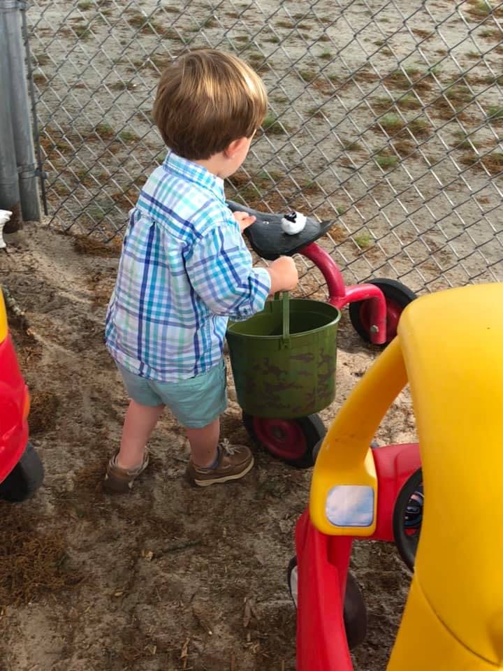 Child playing with a toy and bucket outdoors