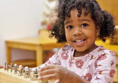 Child playing with a wooden block and metal cylinders