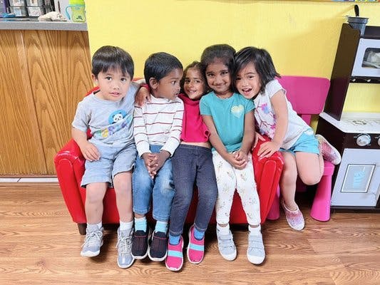 Six children sitting together on a red couch