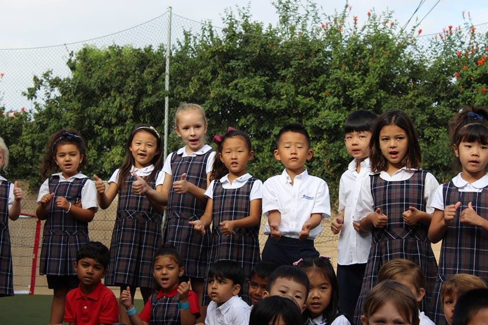 Group of children in school uniforms singing outdoors