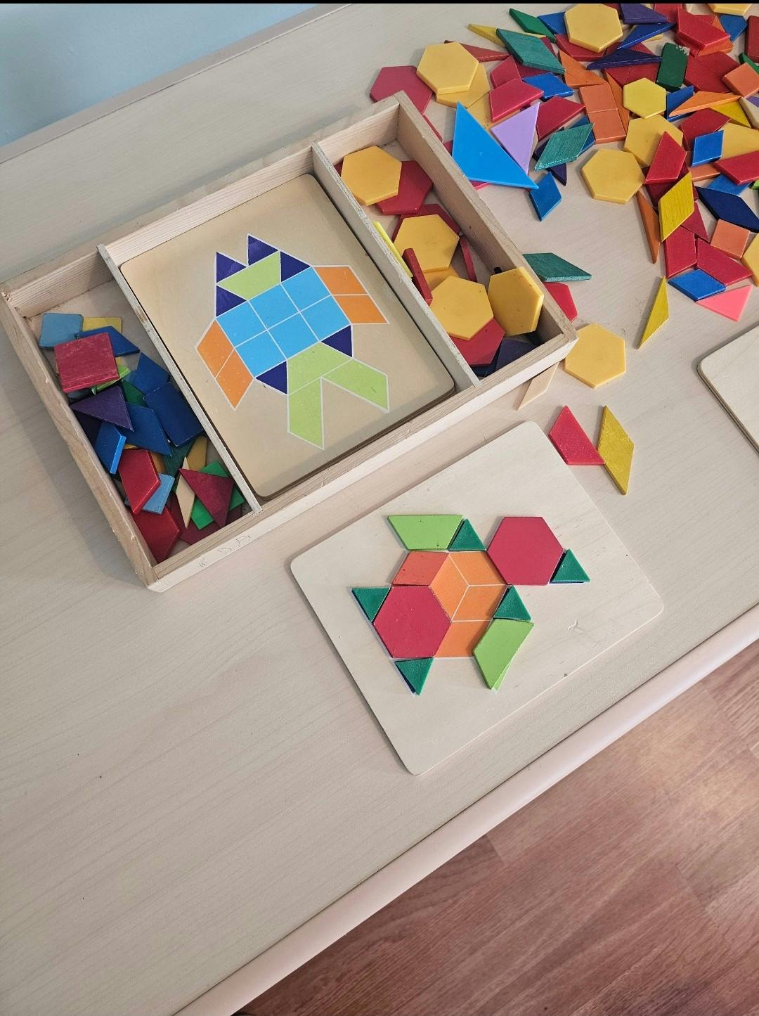 Colorful pattern blocks on a wooden table, some forming shapes